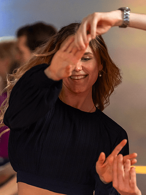 Frau mit dunklem Oberteil beim Tanzen in heller Innenraumumgebung