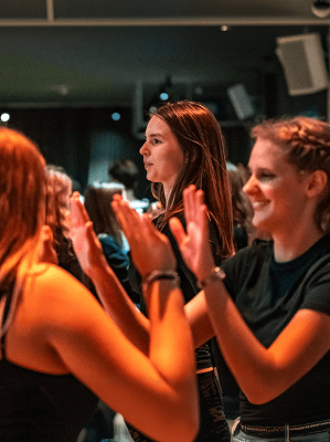 Junge Frauen in lockerer Atmosphäre klatschen und lachen bei einem gemeinsamen Event in Innenraum