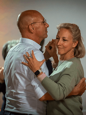 Paar mittleren Alters beim innigen Tanz in heller Innenraumumgebung mit entspannter Atmosphäre