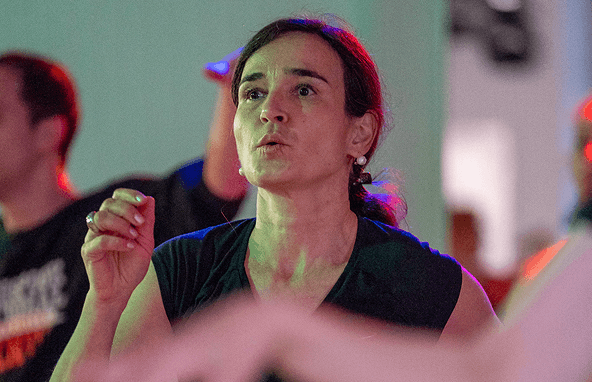 Frau mit dunklem Top in rotem und grünem Licht bei dynamischer Körperbewegung in Innenraum