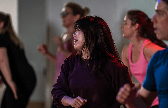 Frauen und Männer in sportlicher Kleidung beim Tanz- oder Aerobic-Kurs in hellem Raum