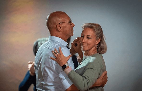 Älteres Paar tanzt eng umschlungen in gemütlicher Innenraumbeleuchtung