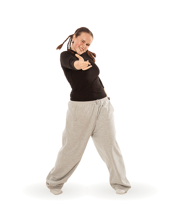 Junge Frau mit Zöpfen trägt schwarzen Pullover und graue Jogginghose posiert dynamisch vor weißem Hintergrund