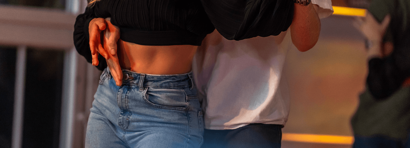 Paar tanzt eng umschlungen in legerer Kleidung in Innenraum mit warmem Licht