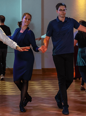 Paar tanzt im Saal auf Parkettboden Frau in blauem Kleid Mann in blauem Polohemd