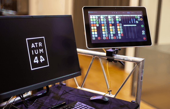 Zwei Computerbildschirme auf schwarzem Tisch, einer zeigt ATRIUM 4A Logo, zweiter Touchscreen mit Steuerungssoftware