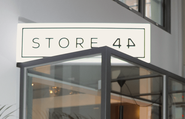 Beleuchtetes Leuchtschild mit schwarzer Aufschrift Store 4P über einem modernen Glaspavillon in heller Innenraumumgebung