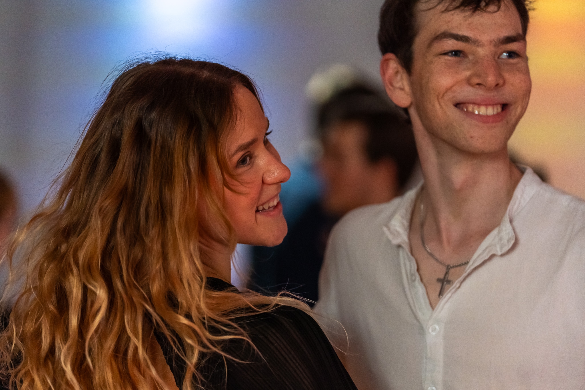 Zwei junge Menschen stehen lächelnd nah beieinander auf einer Tanzveranstaltung