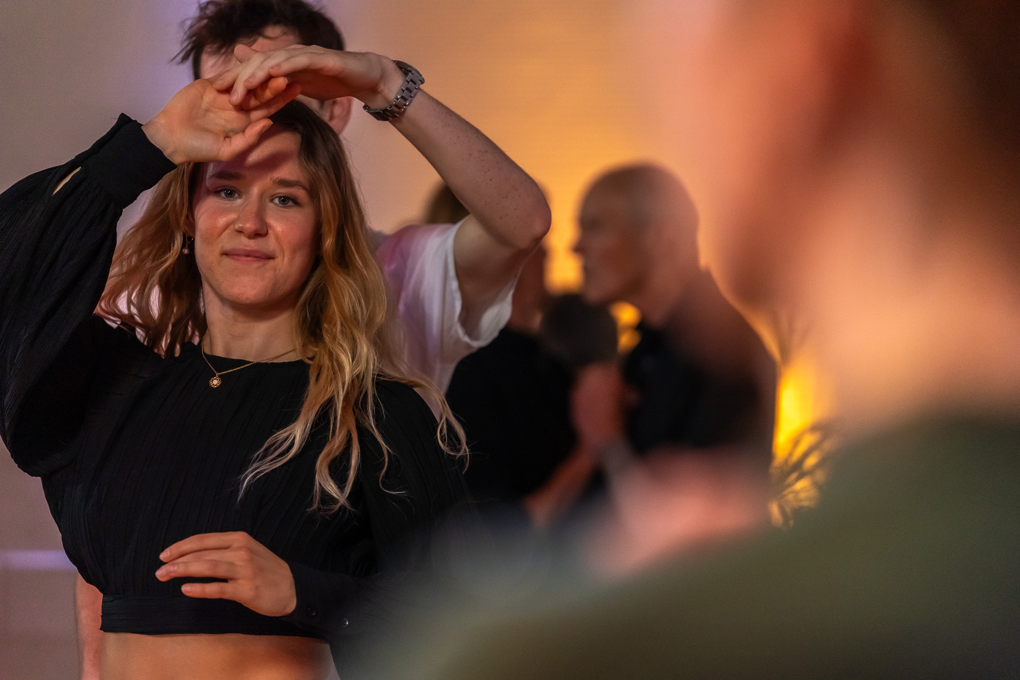 Zwei Personen tanzen lächelnd miteinander auf der Tanzfläche, weitere Tänzerinnen und Tänzer im Hintergrund