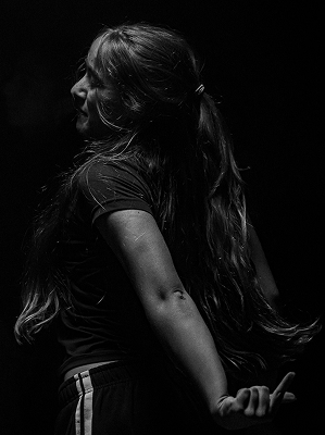 Schwarz-weiß-Porträt einer jungen Frau mit langem Haar im seitlichen Profil vor dunklem Hintergrund