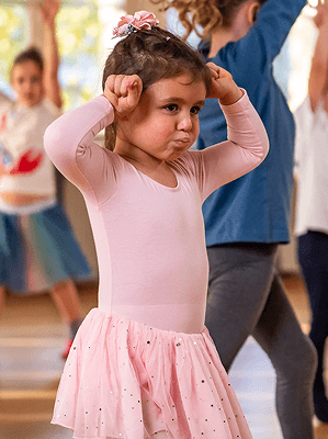 Kleines Mädchen in rosa Ballettkleidung mit Rock in einem Tanzstudio bei einer Übung