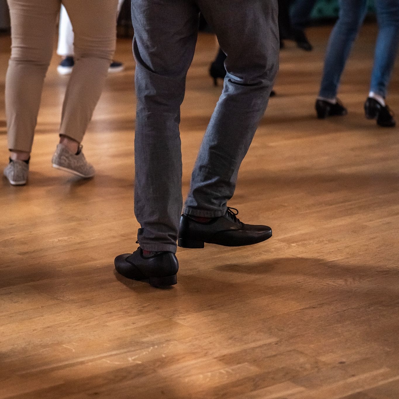 Detailaufnahme von Tanzschritten mehrerer Personen auf dem Parkettboden