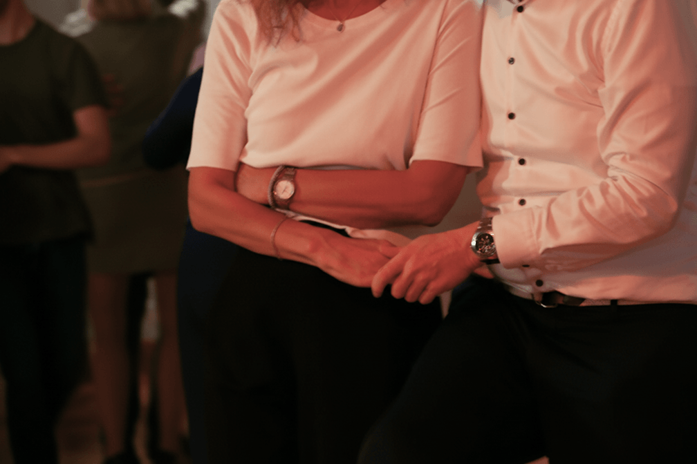 Detailaufnahme eines tanzenden Paares mit verschränkten Armen während eines Paartanzkurses