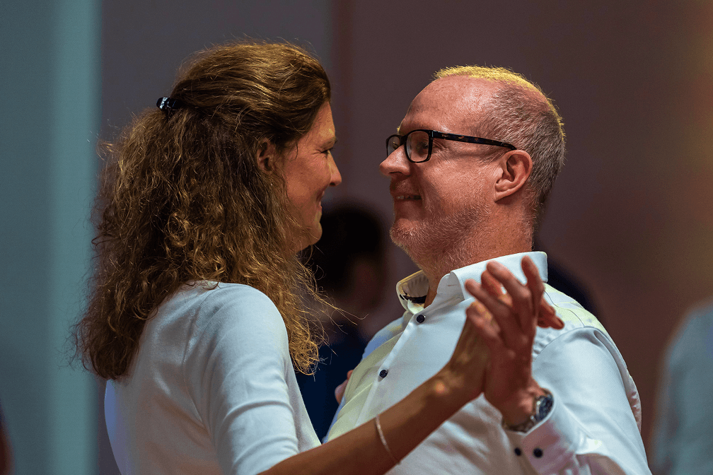 Paar tanzt eng miteinander im Tanzsaal und schaut sich lächelnd an